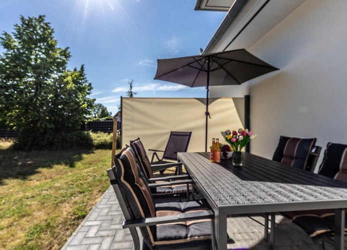 Möblierte Terrasse mit Sonnenschirm und Grill